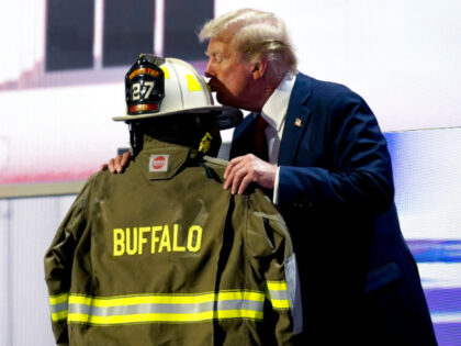 Former US President Donald Trump kisses a firefighter's helmet meant to represent Cor