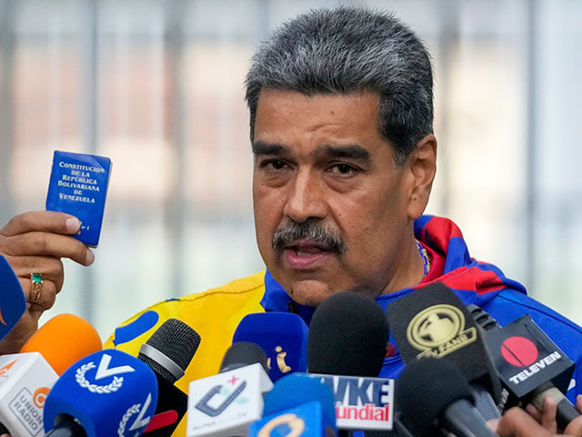 President Nicolas Maduro displays a mini edition of Venezuela's constitution after voting