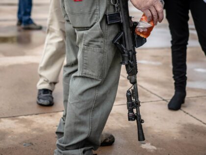 A person carries his assault rifle to a Second Amendment Protest in response to Gov. Miche