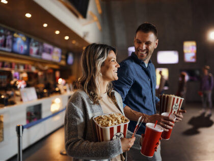 Happy couple bought popcorn and drinks before movie projection in cinema. - stock photo
