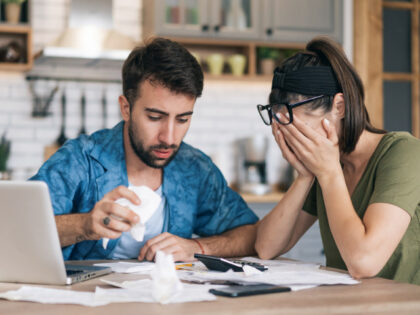 Frustrated concerned young couple calculating overspend budget, doing paperwork job at lap