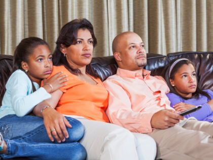 ADDED ON 7/18/24 -- African American family sitting side by side in a row on couch at home