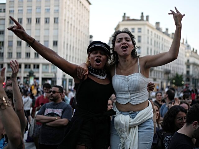 Two women pose as they stand in a square with others during reactions to projected results