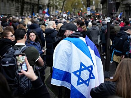 A demonstrator wearing an Israeli flag joins thousands other people for a march against an