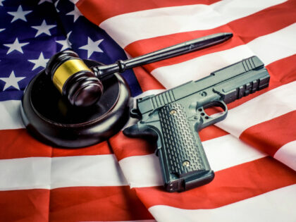 Wooden judge gavel and black color gun over USA flag