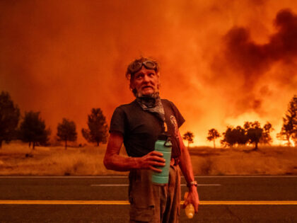 Grant Douglas pauses to drink water while evacuating as the Park Fire jumps Highway 36 nea