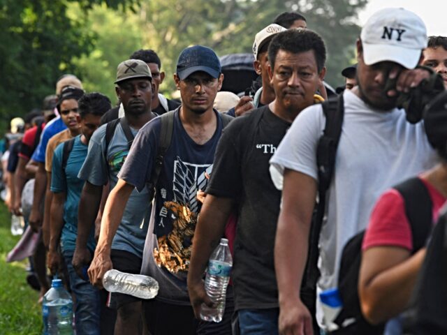 Migrants, mostly from Central America and Venezuela, walk towards the United States on the