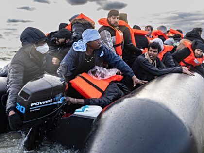 Migrants board a smuggler's boat in an attempt to cross the English Channel, on the beach
