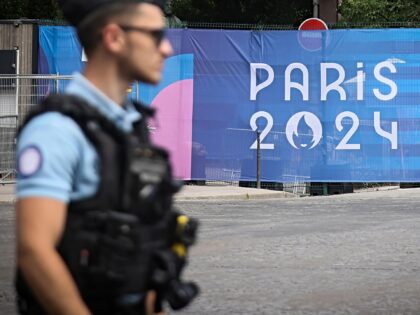 FILE - A police officer walks past a Paris Olympics canvas at the 2024 Summer Olympics, Sa