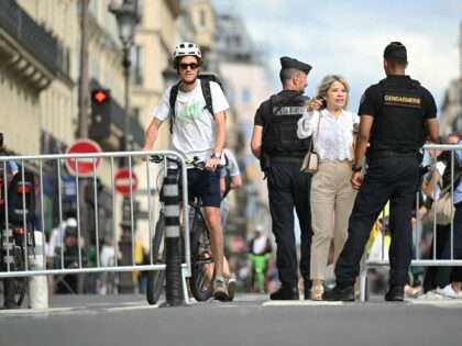A visitor gestures next to French gendarmes controlling a restricted area in central Paris