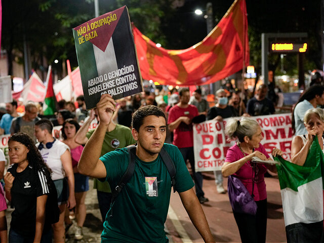 A man holds a sign that reads in Portuguese "No to the occupation of Gaza" as he participa