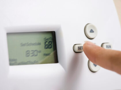 Setting electronic thermostat heat to 68 degrees - stock photo