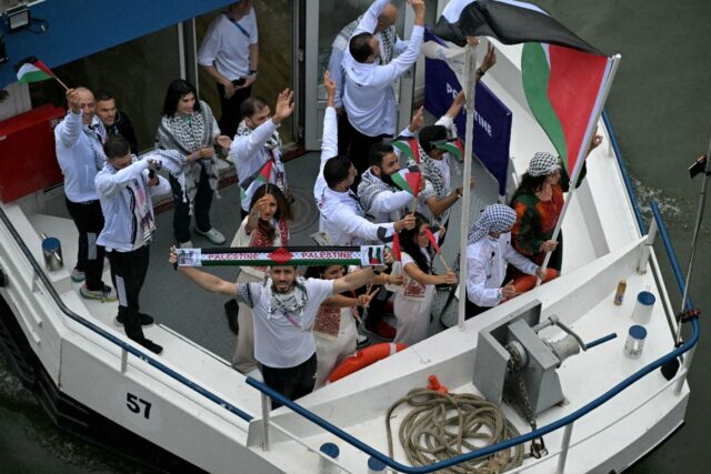 Abu Sel can be seen holding the flag as the Palestinian delegation sailed up the Seine dur