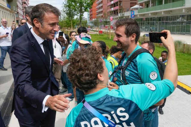 Emmanuel Macron poses for a selfie as the French president meets volunteers at the Athlete