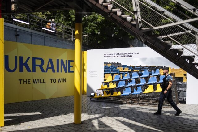 A French gendarme walks past damaged seats from a stadium in Ukraine displayed at the coun