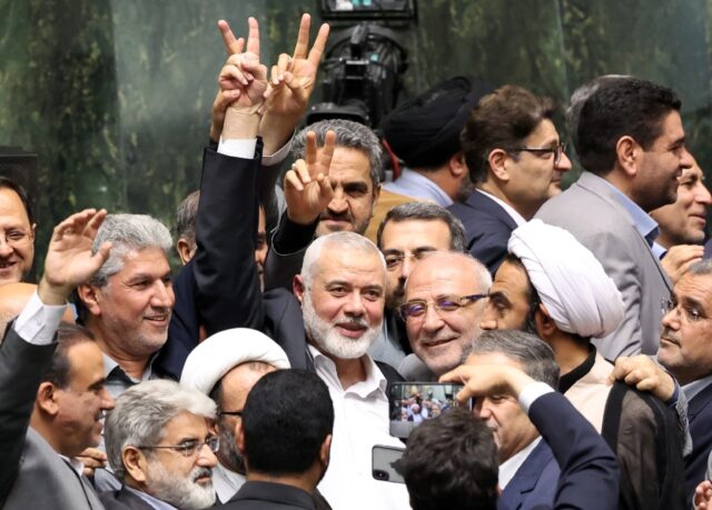 Hamas political leader Ismail Haniyeh flashes a victory sign during the swearing-in of Ira