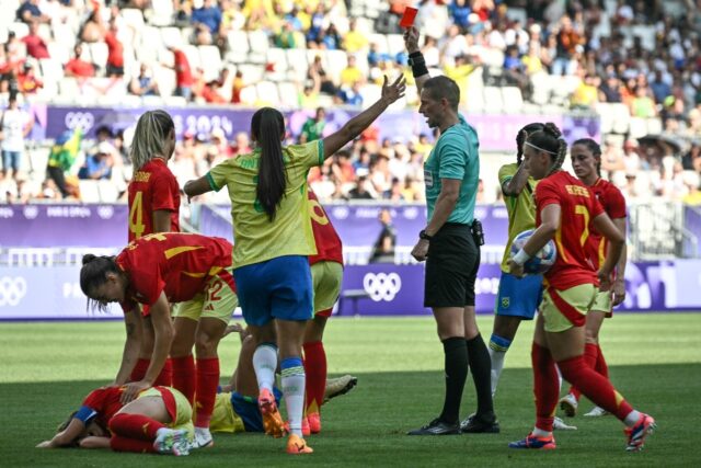 The Norwegian referee brandishes a red card to Marta, who is on the ground, during Brazil'