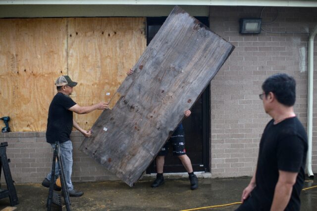 A group of men board up a restaurant in Port Lavaca, Texas, on July 7, 2024, as they prepa