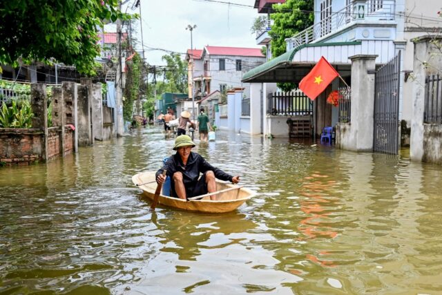 A man rowing a boat through floodwaters in Ben Voi village on the outskirts of Hanoi on Ju