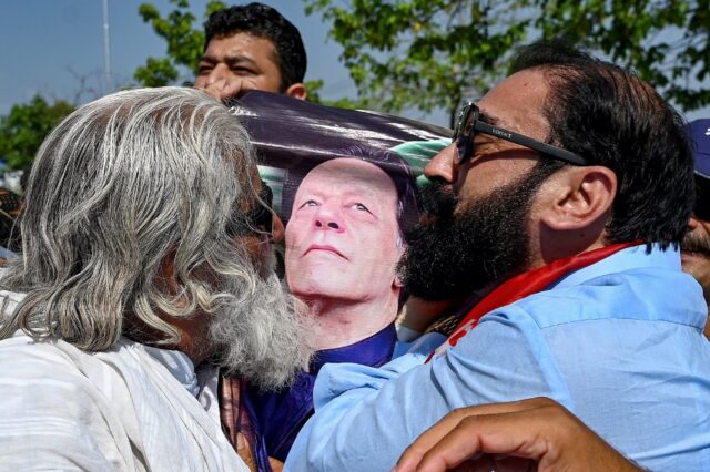 Supporters of Pakistan's former prime minister Imran Khan kiss a poster with his portrait