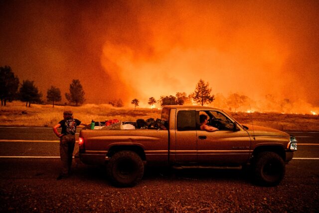 Surrounded by flames, residents pull over on the side of the road while evacuating due to