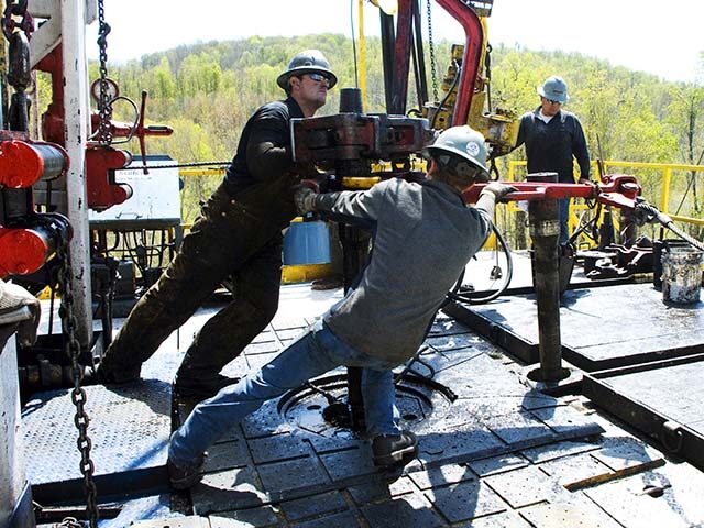 Workers move a section of well casing into place at a Chesapeake Energy natural gas well s