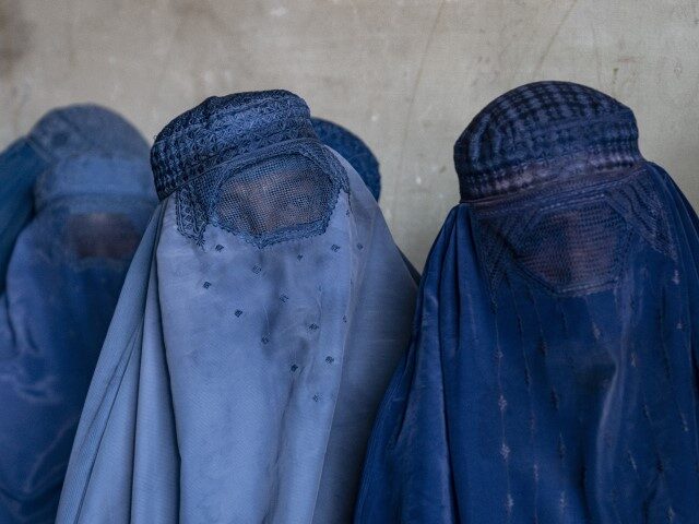 Afghan women wait to receive food rations distributed by a humanitarian aid group, in Kabu