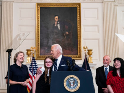 US President Joe Biden, center left, embraces Miriam Butorin, daughter of Alsu Kurmasheva,