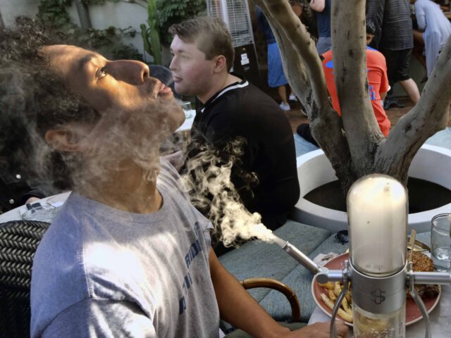 A man takes a puff from a marijuana pipe joined his girlfriend Vannessa Hursey during his