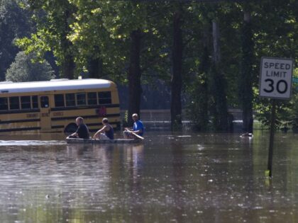 Residents paddle down flooded streets past a stranded school bus in Live Oak Fla., Wednesd