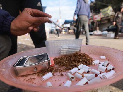 A man rolls cigarettes to sell on the street in Rafah in the southern Gaza Strip on March