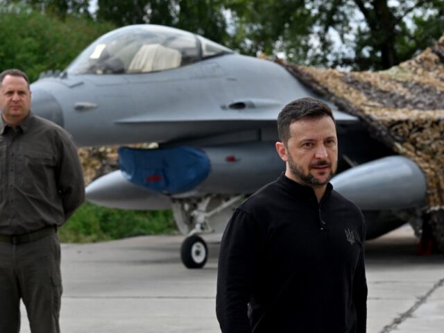 Ukraine's President Volodymyr Zelensky (C) stands in front of an F16 fighter jet during a