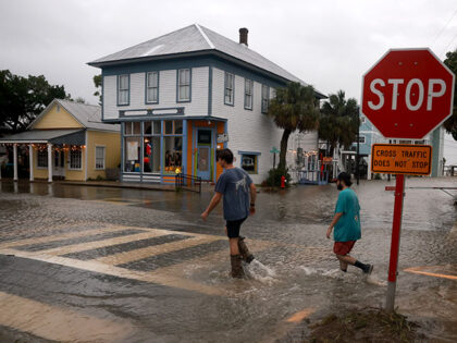 People walk through a flooded street caused by the rain and storm surge from Hurricane Deb