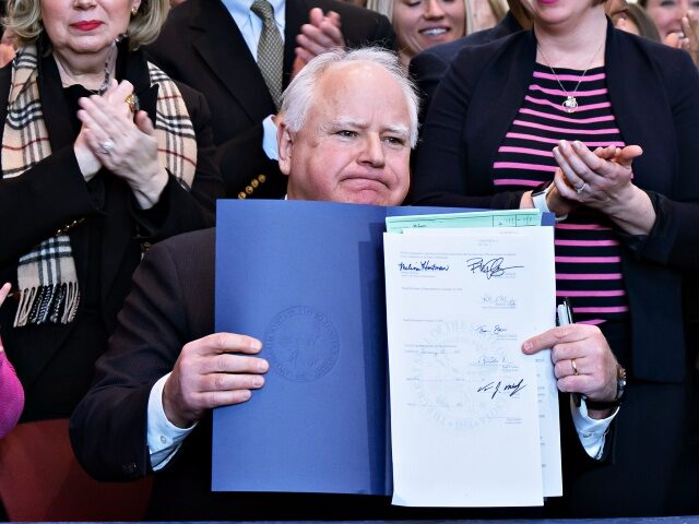 Surrounded by DFL legislators, Gov. Tim Walz signs a bill to add a "fundamental right