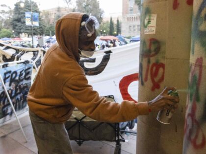 A demonstrator sprays graffiti on a building on the UCLA campus, Wednesday, May 1, 2024, i