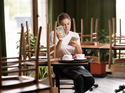 Waitress counting salary or tips in dollars while sitting in a cafe, give the waiter a tip