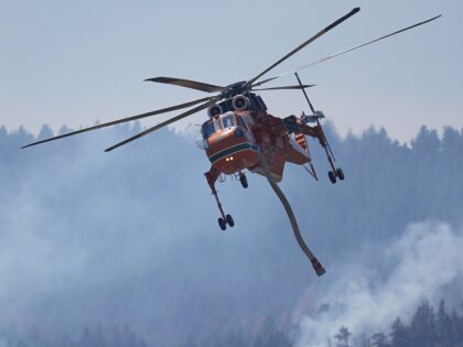 A helicopter heads in for a water drop as the Quarry wildfire burns in the foothills near