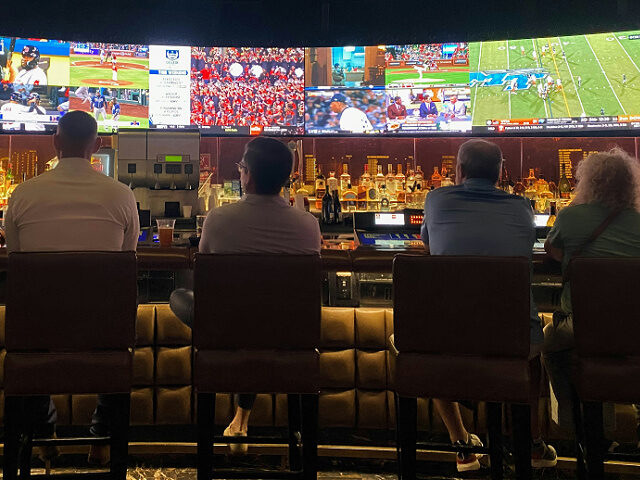 a group of people sitting at a bar watching sports on tv