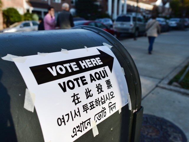 A directional sign in various languages is placed to point voters to a polling station in