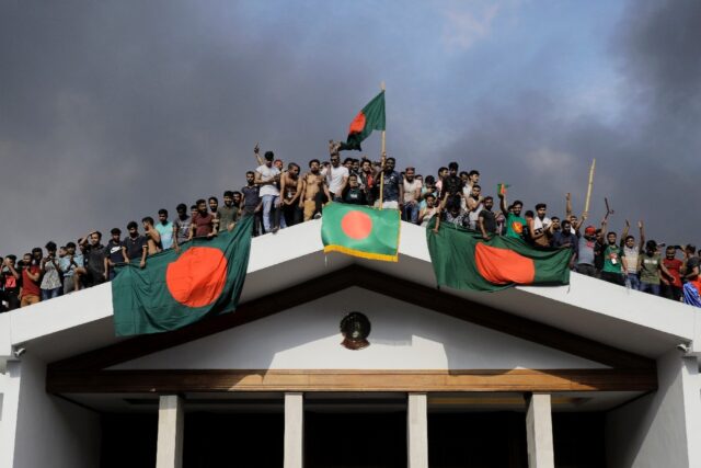 Anti-government protestors display Bangladesh's national flag as they storm Prime Minister