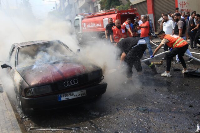 Lebanese firefighters put out a fire in a car after an Israeli strike in the southern city