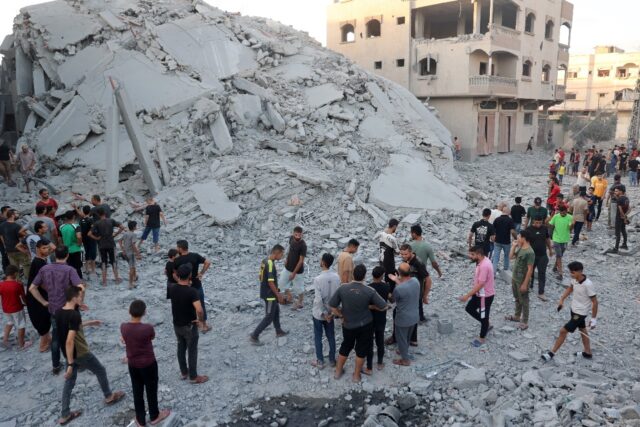 Palestinians check the remains of a building shortly after Israeli bombing levelled it in