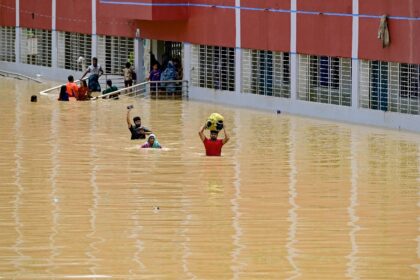 People wade through floodwaters outside a temporary shelter in Feni; more than 307,000 peo