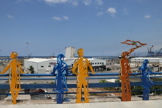 Sculpted figures representing people staring at the devastation are lined up along the roa