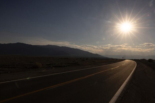 The sun sets over a highway in California