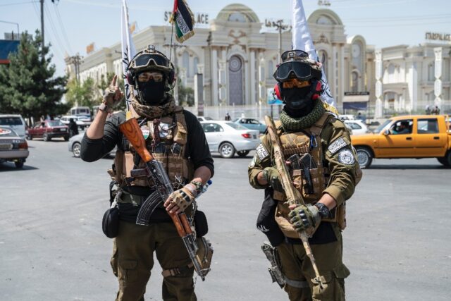 Taliban security personnel stand guard along a Kabul road on the eve of the third annivers