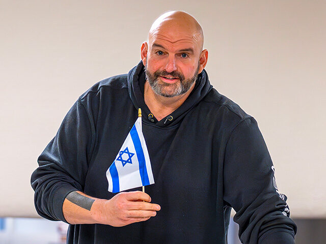 Sen. John Fetterman, D-Pa., holds a small Israel flag as he heads to the chamber for a vot