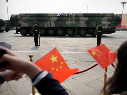 Spectators wave Chinese flags as military vehicles carrying DF-41 nuclear ballistic missil