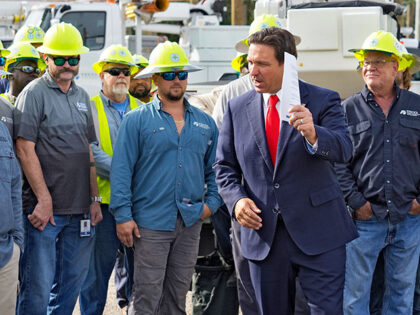 Florida Gov. Ron DeSantis, second from right, speaks to linemen before a news conference,