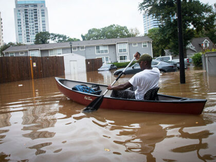 An unidentified man paddles a canoe to rescue residents and their belongings at a flooded